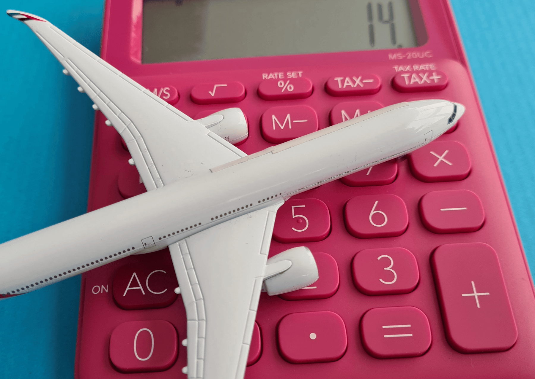 un avion jouet posé sur une calculatrice rouge